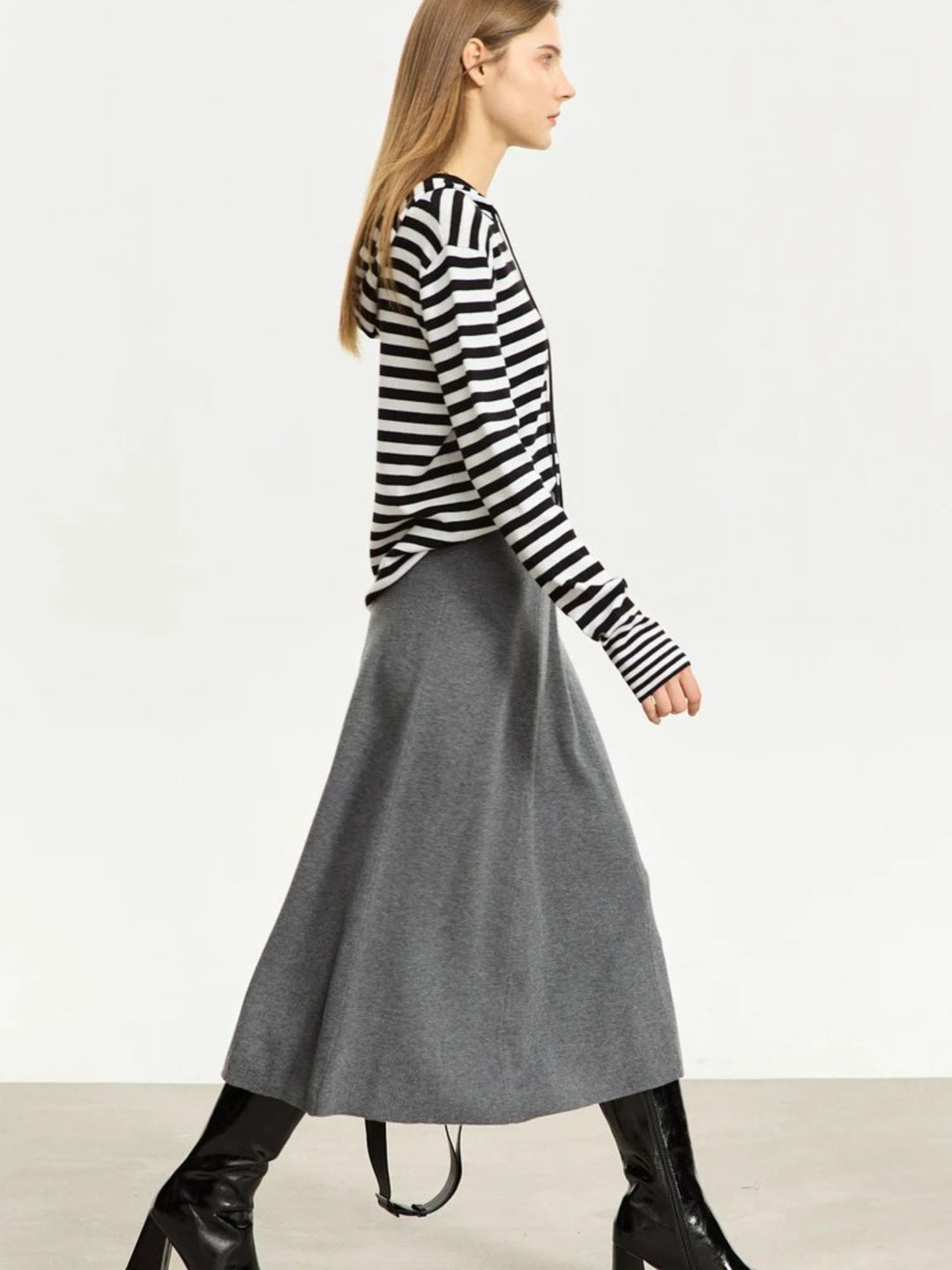 Grauer A-Linien-Midirock aus Wolle, Modell gehend mit Streifenpullover.