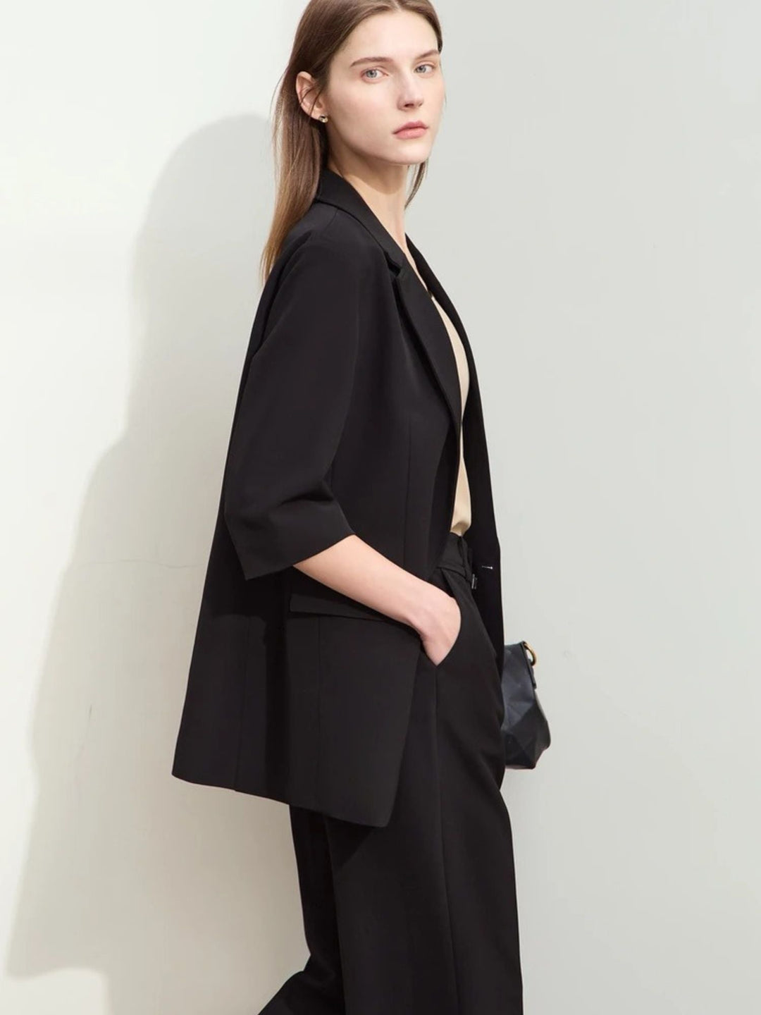 Schwarzer Damen-Hosenanzug mit weitem Blazer, Modell seitlich mit Tasche.