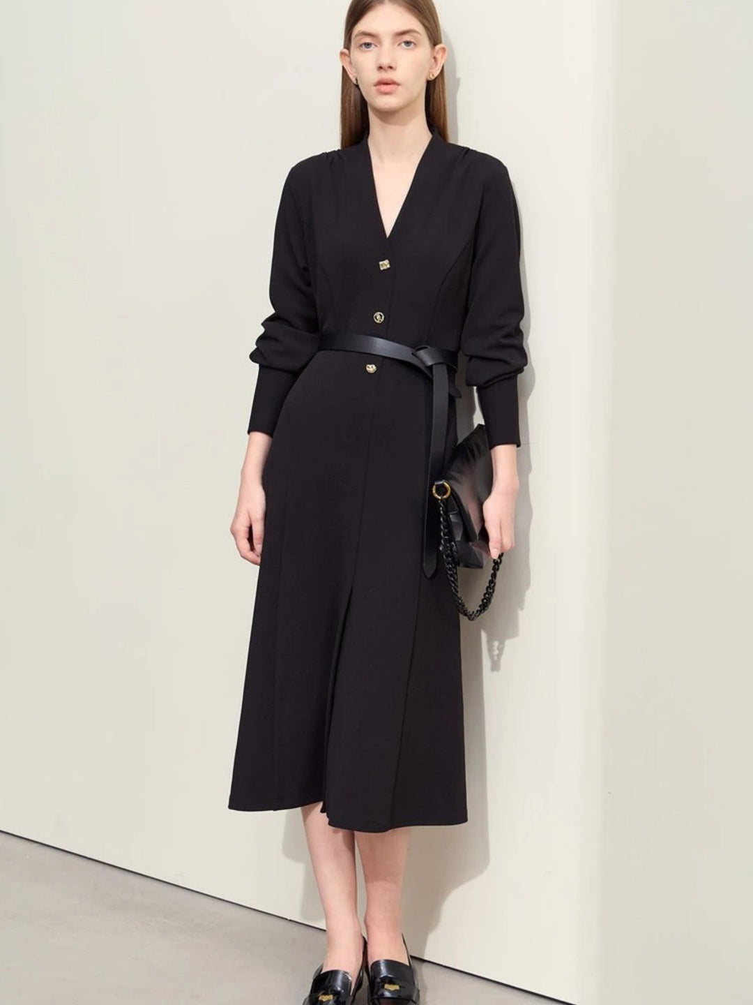 Schwarzes Midikleid mit V-Ausschnitt, Modell frontal mit Tasche.