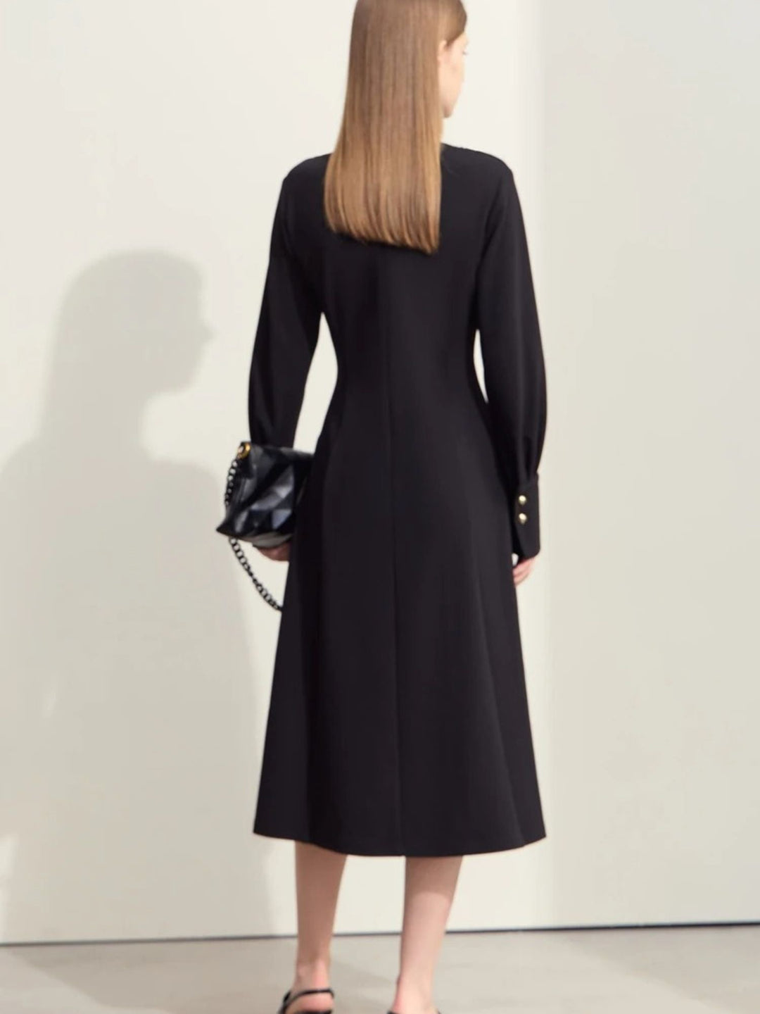 Schwarzes Midikleid, Rückansicht des Modells mit Handtasche.