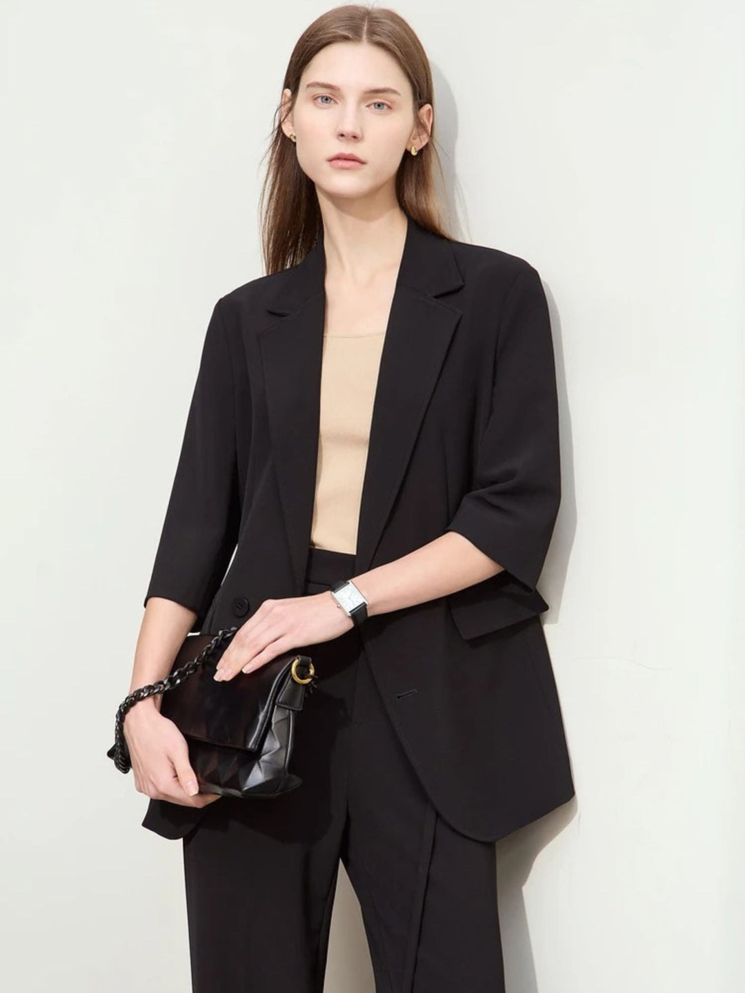 Schwarzer Hosenanzug mit 3/4-Arm-Blazer, Modell frontal mit Clutch.