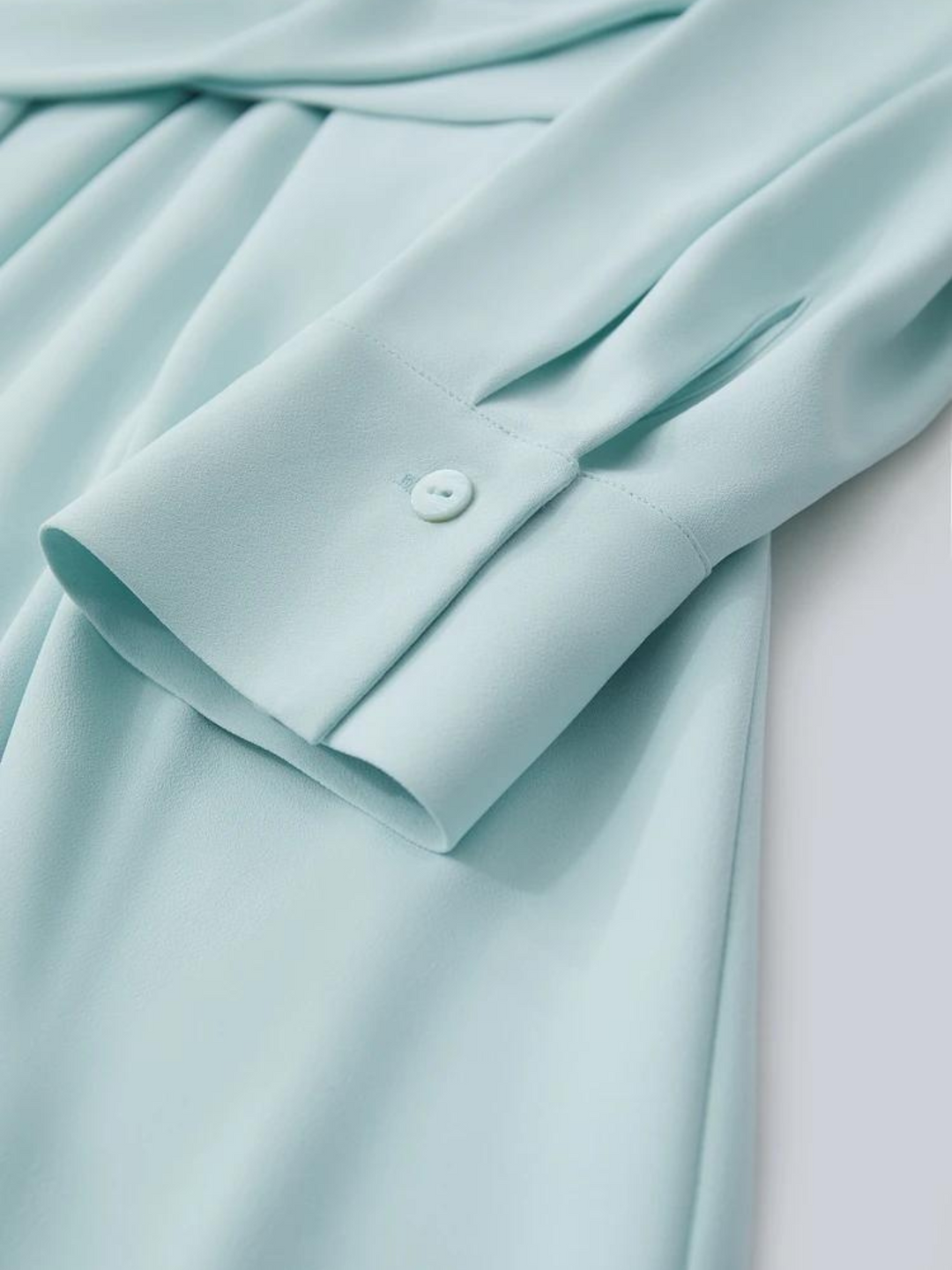Close up of the details of the cuff of a powder blue dress.